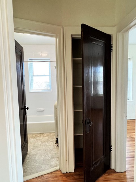 a closet in a bedroom with a door open to a bathroom with a tub and a window